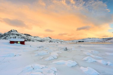 Norveç 'teki Lofoten Adaları ve gün batımındaki güzel kış manzaraları. Karla kaplı plajda kırmızı evi olan Idyllic manzarası. Kuzey Kutup Dairesi 'nde turistik cazibe.