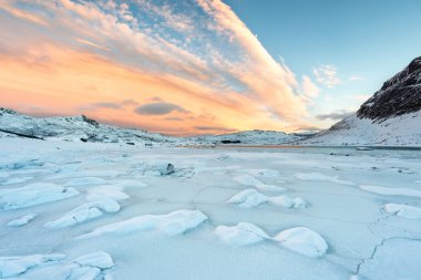 Norveç 'teki Lofoten Adaları ve gün batımındaki güzel kış manzaraları. Karla kaplı plajı olan huzurlu bir manzara. Kuzey Kutup Dairesi 'nde turistik cazibe.