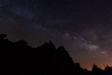 Yıldızlarla dolu bir gökyüzü ve güzel Samanyolu ile karanlık bir gece. Doğanın gece manzarası harikası.