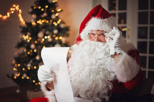 Santa Claus Olvasó Ból Egy Hosszú Listát Hangulatos Szobában — Stock Fotó
