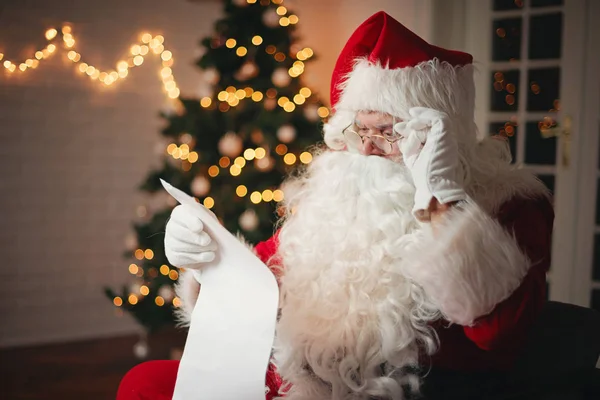 Santa Claus Olvasó Ból Egy Hosszú Listát Hangulatos Szobában — Stock Fotó