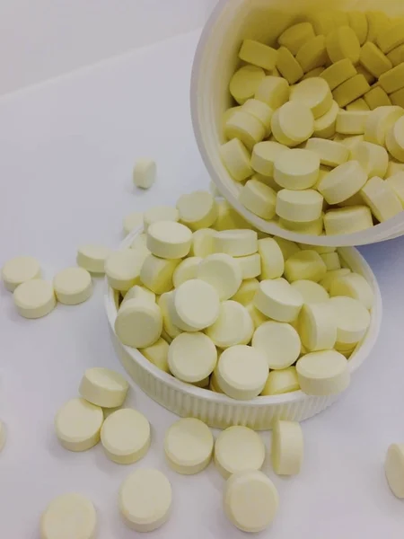 Süt tablet beyaz plastik şişeden beyaz arka plan üzerinde izole kapak içine dökülür varlık.