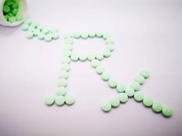 Pharmacy symbol, Rx word made by light green tablets isolated on white background. copy space and selective focus.