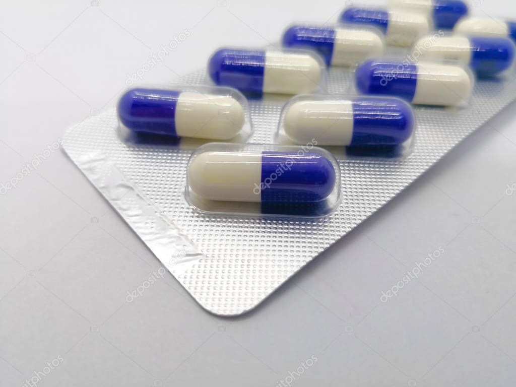 Medication concept. Fluconazole is anti-fungal medicine, that are blue-white capsules in the silver blister. Isolated on white background, focus on foreground and copy space. 