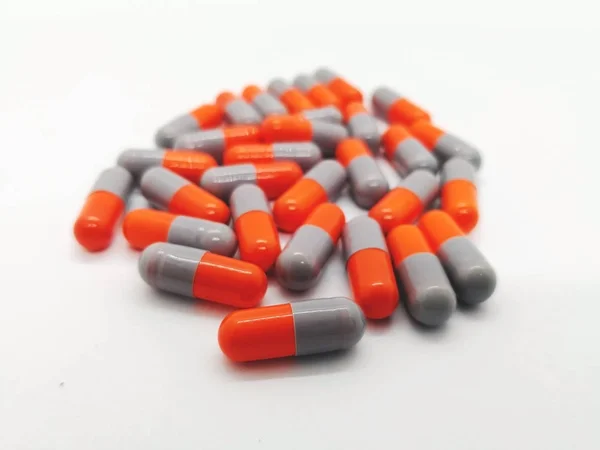 İlaç ve sağlık kavramı. Sefaleksin 250 mg. bakterilerin neden olduğu enfeksiyonların tedavisinde kullanılan beyaz zemin üzerine izole birçok gri-turuncu kapsül. Ön plan ve kopya alanı üzerinde odaklanmak.