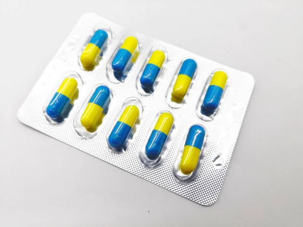 İlaç ve sağlık kavramı. Birçok mavi-sarı kapsül piroksikam 20 mg., gümüş blister içinde olan. Kas inflamasyon ve azaltılmış ağrı tedavisinde kullanılır. Beyaz arka plan üzerinde izole, ön plan ve kopya alanı üzerinde odaklanmak.