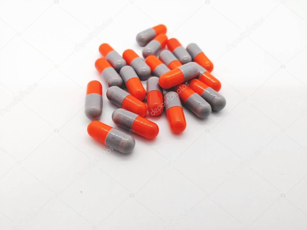 Medication and healthcare concept. Many gray-orange capsules of Cephalexin 250 mg. isolated on white background, used to treat serious infections caused by bacteria. Focus on foreground and copy space.