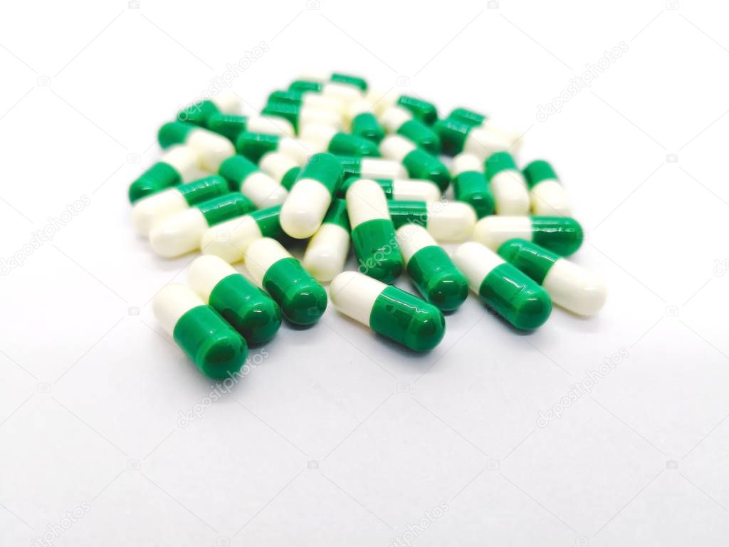 Medication and healthcare concept. Many white-green capsules of Tramadol 50 mg., it is a narcotic-like pain reliever. Used to treat moderate to severe pain. Isolated on white background, focus on foreground and copy space.