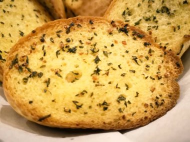 Baget ekmek tereyağı ve sarımsak, bir parça kağıt ile hasır sepet içinde olan ile dilimlenmiş. Ve bu ahşap masa restoran bulunmaktadır. Bulanık arka plan ve kopya alanı.