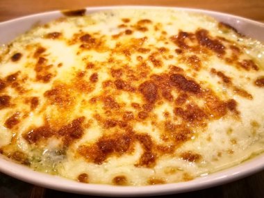 Beyaz kase içinde peynir ile ıspanak pişmiş, ahşap masa restoranda açıktır. Seçici odak ve kopya alanı. 