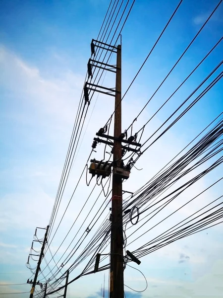 Three-phase electric poles on road side, that is common in Thailand. The electric lines, telephone lines and internet lines are within the same pole. Selective focus and copy space.