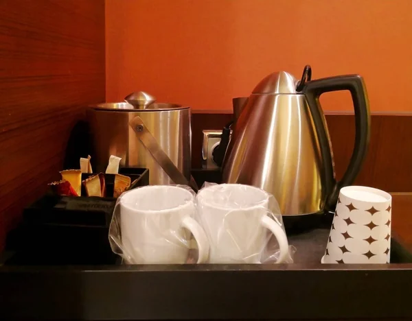 Gıda kavramı. İçki, hazır kahve, çay, kupa ve elektrikli su ısıtıcısı olan köşe. Bunlar ahşap tepsiye yerleştirilir. Kopya alanı.