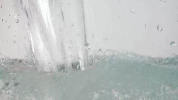 Eau coulant sur la surface, éclaboussures et se levant avec des bulles sur fond blanc. Prise de vue de gros plan sur l'eau coulée. Tourné au format HD 60fps 