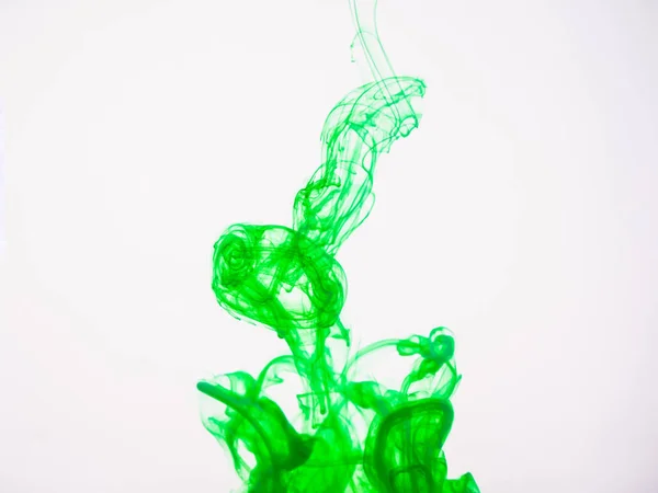 Зелений акриловий колір розчиняється у воді, крупним планом. Абстрактний зелений кольоровий фон. Акрилова фарба впала у воду і сфотографувалася під час руху. Крапля кольору на білому тлі . — стокове фото