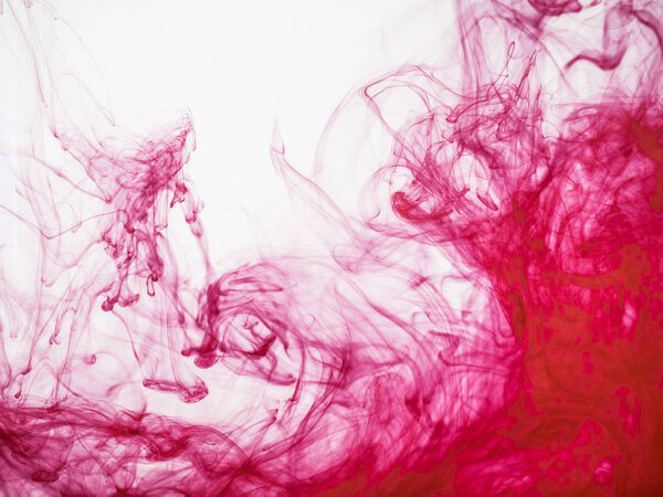 Close up view on red acrylic ink under water. Red acrylic ink explosion, abstract background. Colourful splash of paint dissolving into water. Abstract acrylic background