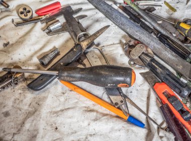 El aletleri ev bir tezgah üzerinde kirli kümesini kapatın. Ev tezgah kirli beyaz örtüyle kaplı tozlu el aletleri dolu. Farklı el aletleri, tam bir düzensiz eve ahşap yakın çekim.