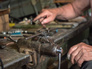 Tezgah üzerinde evde monte Iron grip üzerinde yakın atölye. Farklı demir yumruk instrumets tam bir mutfak. El mans iş süreci, görünümü kapatın. Arka plan bulanık, yumuşak seçici odak.