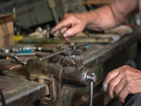 Tezgah üzerinde evde monte Iron grip üzerinde yakın atölye. Farklı demir yumruk instrumets tam bir mutfak. El mans iş süreci, görünümü kapatın. Arka plan bulanık, yumuşak seçici odak.