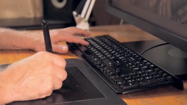 Designer zeichnen auf digitalem Tablet mit Touchscreen-Stift, aus nächster Nähe. Eine Hand zeichnet auf einem Tablet-Computer, eine andere klickt auf Tasten auf der schwarzen Tastatur. verschwommener Hintergrund, weicher selektiver Fokus. — Stockvideo