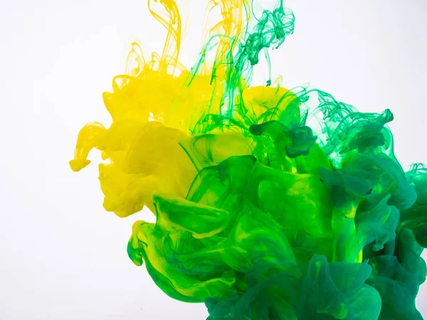 Proces van acryl inkt mengen onder water close-up. Gele en groene verf oplost in water, abstracte achtergrond. Twee druppels van acryl inkt oplost in water. — Stockfoto