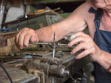 Vida dişi açma işlemi Görünümü kapatın. Vida kesme devam ediyor. Yaşlı bir adam ev tezgah çalışma. Yakın çekim, işçi iş parçacığı kesme yapar. Arka plan bulanık, yumuşak seçici odak.