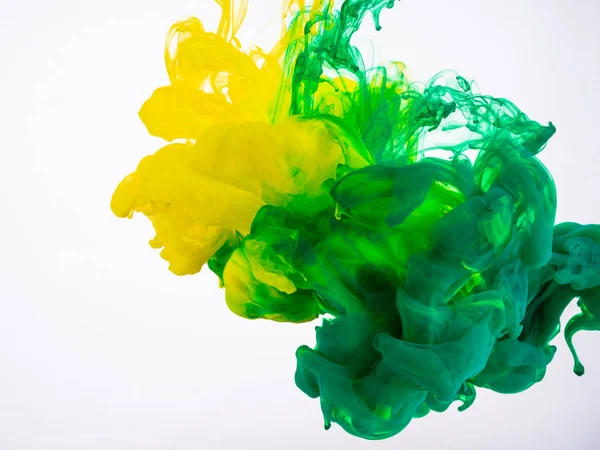 Gele en groene acrylverf maken een abstracte explosie onder water. Twee inkt kleuren mengen in vloeistof, geïsoleerd op witte achtergrond. Geel-groene acrylinkt explosie onder water. — Stockfoto