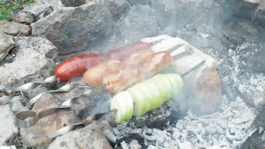 Sosis ve brochettes içinde şömine üzerinde Impaled soğan. Bahçede ızgara bir açık hava. Sosis üzerinde yanan köz hazırlanıyor. Ev yapımı ızgara ile gri taş döşeli. Sosis üzerinde tükürür, yakın çekim.