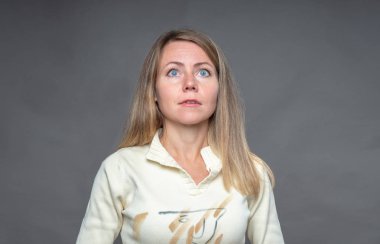 Kadın duygu. Umut ve beklenti ile ilham kadın örnek alıyor. Akan sarışın kız. Beden dili ve gerçek duygular. Stüdyoda çekim gri arka plan üzerinde duygusal kadın portresi.