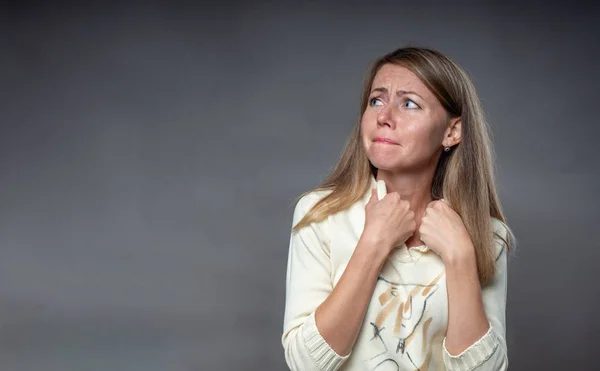 Woman emotion. A frightened woman with upset feelings. Offended and crying girl. Body language and real feelings. Portrait of emotional woman over gray background shooting in studio.
