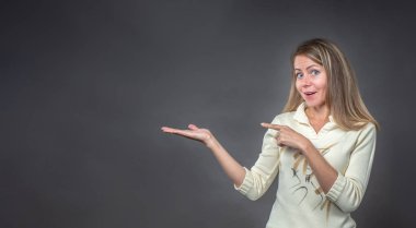 Sürpriz esmer tutan eller ve sevindim sloganı, reklam ürünleri, kısa mesaj için boş yeri alanı sunmak için. Kız için bir şeyler bazı ürün gösteriyor. Gri arka plan üzerinde izole.