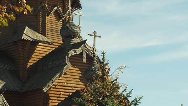 Biara kayu kuno di Ukraina. Kubah dengan salib dan ukiran dekoratif kayu. Tembakan biasa. Puncak cemara di depan biara. Musim gugur di biara. Latar belakang kabur. Fokus lembut selektif . — Stok Video