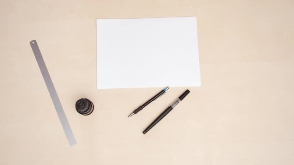 Mans mains sur le bureau calligraphique. Plan rapproché. Vue de dessus. Blancs blancs, règle, deux stylos à brosse sur fond beige. Position du bras sur le lieu de travail des concepteurs. Un homme posant ses mains sur un bureau beige. Lettres . — Video