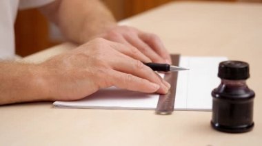 Çizgiler cetvel ve fırça kalemle çizim eller mans. Yakın çekim. Yan görünümü. Tasarımcı iş başında. İnkpot bej çalışma alanı üzerinde. Caligraphic yazı için hazırlanıyor. Boş çizim satırlarda. Arka plan bulanık.