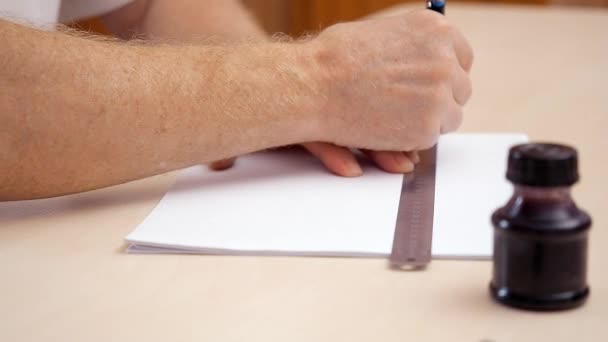 Manos de hombre dibujando una línea en blanco blanco con regla y pluma de pincel. Muy cerca. Vista lateral. Ver en el lugar de trabajo diseñadores. Preparación para letras caligráficas. Fondo borroso. Tintero sobre escritorio beige . — Vídeos de Stock