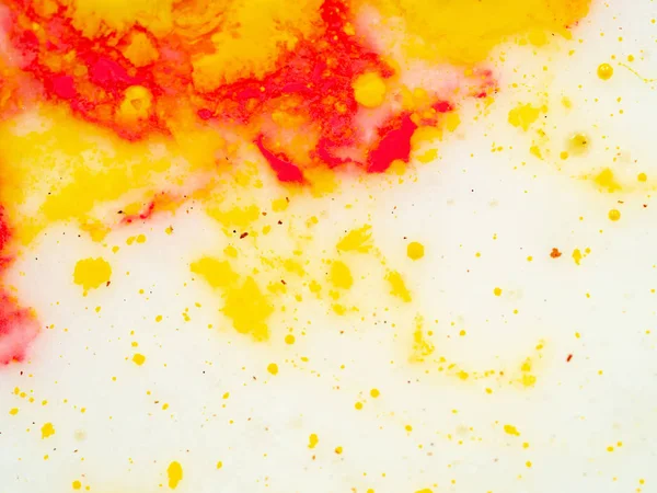 Splashes of red and yellow paint, abstract background. Close up shot. Blurred background. Abstract pattern on white background. Colourful splashes of yellow and red paint. Macro shot.