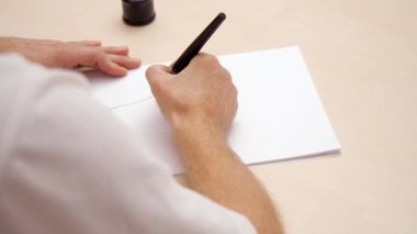 Beyaz boş mektup yazma sanatçı. Yakın çekim. Üstten Görünüm. Kaligrafi fırçası kalemle yazı. Adam beyaz boş çizim. Yazma calligraphist. Seçici yumuşak odak. Arka plan bulanık.