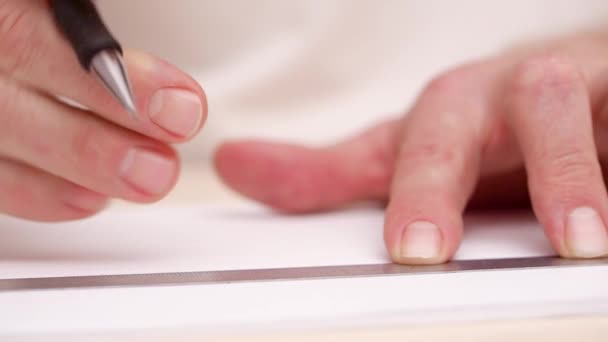 Manos de hombre dibujando líneas en blanco blanco. Muy cerca. Vista frontal.Líneas de dibujo caligráfico con pluma de pincel. Diseñador hace líneas con regla de hierro. Letras caligráficas. Fondo borroso . — Vídeos de Stock