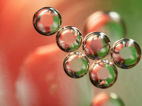 Abstract geometrical figure of glittering spheres. Close up shot. Blurred background. Selective soft focus. Abstract background. Scores of spheres glittering with green and pink lights. Macro shot.