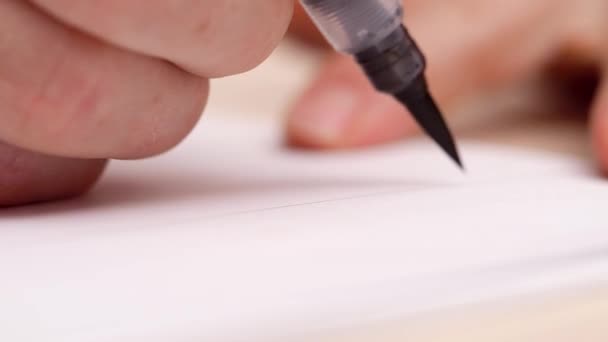 Calligraphe dessinant des lettres à blanc blanc. Plan rapproché. Vue latérale. Lettrage calligraphique avec peinture noire. Designer au travail. Lettres d'artiste. Mise au point sélective. Fond flou .