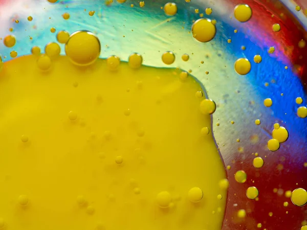 Drops of yellow paint on multicolour background. Close up macro shot. Selective soft focus. Abstract background of paint drops and spots. Colorful paint on glass. Multicolour universe of ink drops.