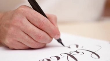 Harfler beyaz boş çizim calligraphist. Yakın çekim. Önden Görünüm. Kaligrafi yazı. Beyaz boş yazma el mans. Tasarımcı iş başında. Seçici yumuşak odak. Arka plan bulanık.