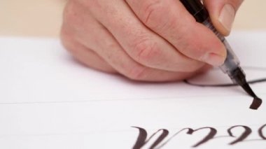 Beyaz boş çizim calligraphist. Yakın çekim. Önden Görünüm. Fırça kalemi ile üzerine beyaz boş yazma el mans. Kaligrafi yazı. Tasarımcı çizim. Seçici yumuşak odak. Arka plan bulanık.