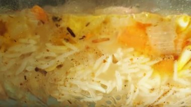 Yemek yemek, sebze ve et ile yulaf lapası pirinç. Cam tencerede pilav kaynar. Yakın çekim görünümü. Pirinç havuç, sarımsak, soğan ve et. Ulusal Asya gıda.
