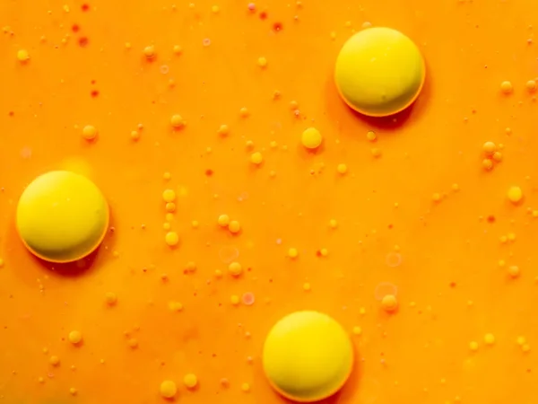 オレンジ色の背景に 3 つの黄色の球。クローズ アップのマクロ撮影します。背景をぼかし。選択的なソフト フォーカス。オレンジ色の宇宙、抽象的な背景。大小の気泡、抽象的なパターンのスコア. — ストック写真