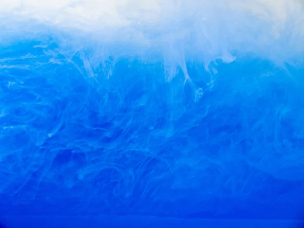 Akrylové inkoust rozpustí do vody, detailní zobrazení. Abstraktní pozadí. Modrá barva v kapalině. Akrylové mraky ovíjející se ve vodě. Modrý inkoust vlny v kapalné, abstraktní vzor. Rozmazané pozadí. — Stock fotografie