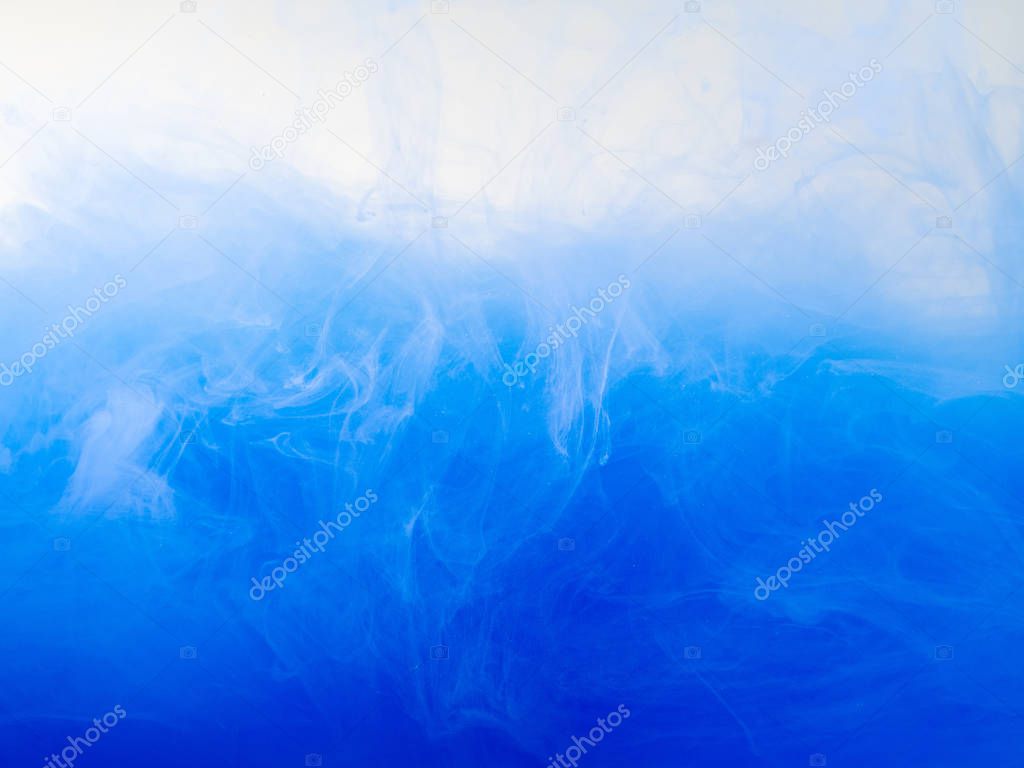 Drop of blue paint dissolving into water, close up view. Abstract background. Acrylic clouds swirling in liquid. Waves of acrylic ink in water, abstract pattern. Paint in liquid. Blurred background.