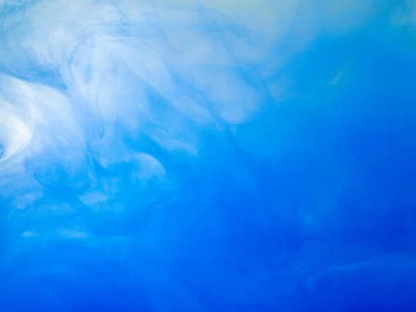 Kapka modrého akrylového inkoustu ve vodě, pohled zblízka. Abstraktní pozadí. Akrylové mraky vířící v tekutině. Vlny barvy ve vodě, abstraktní vzorec. Rozpouštění inkoustu do kapaliny. Rozmazané pozadí. — Stock fotografie