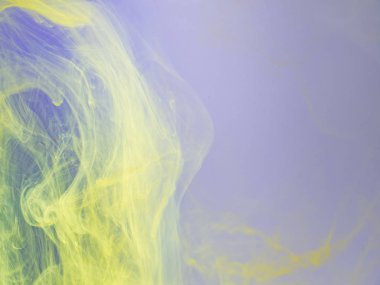 Suda sarı ve eflatun akrilik boya, yakın görüş. Arka plan bulanık. Akrilik ışık bulutları suda çözünüyor, soyut arkaplan. Mürekkep sıvıyla karışımı, soyut desen.