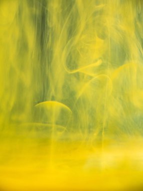 Suyun altında soyut akrilik duman. Yakından görüş. Bulanık arka plan. Seçici yumuşak odak. Sarı mürekkep damlacıkları suya eritiyor, soyut desen. Sıvı ile boya karıştırma.