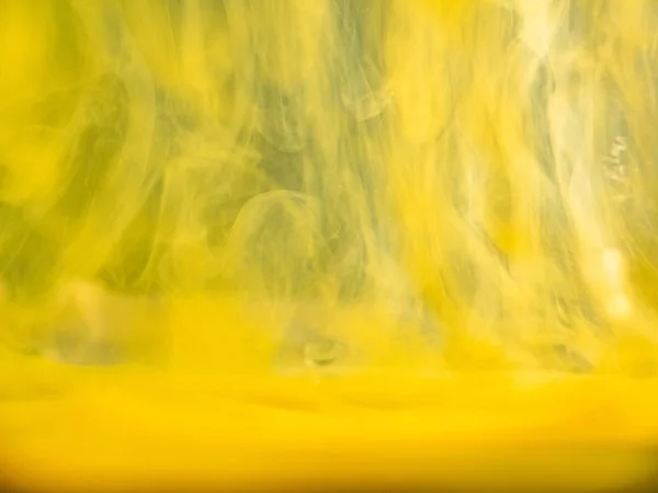 Abstract yellow pattern, close up view. Blurred background. Yellow acrylic flows dissolving into water, abstract background. Ink mixing with liquid, background for abstract wallpapers and banners.